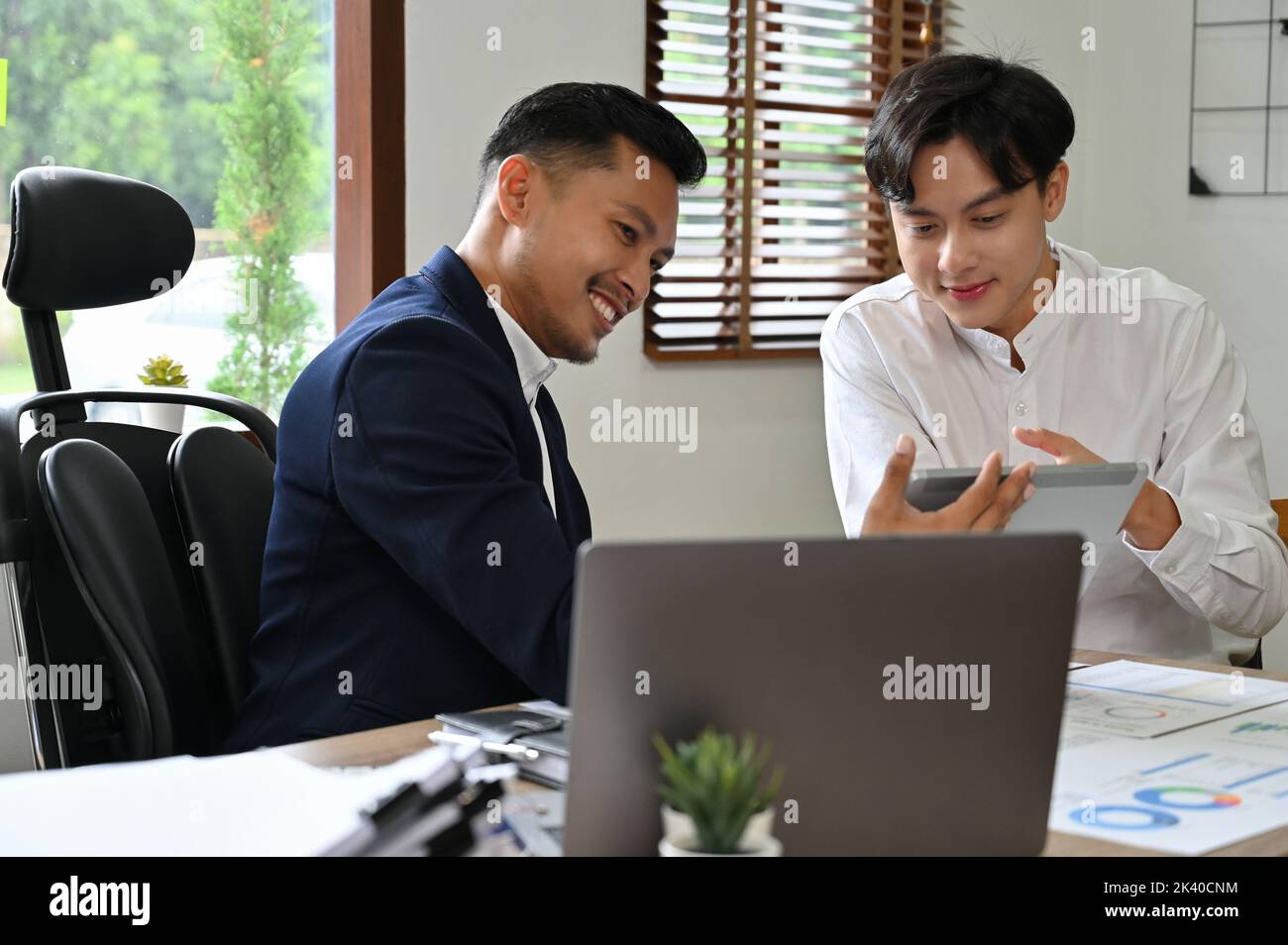 Un jeune analyste financier ou un travailleur financier asiatique intelligent, montrant et expliquant ses données d'analyse financière à son patron masculin au bureau. Banque D'Images
