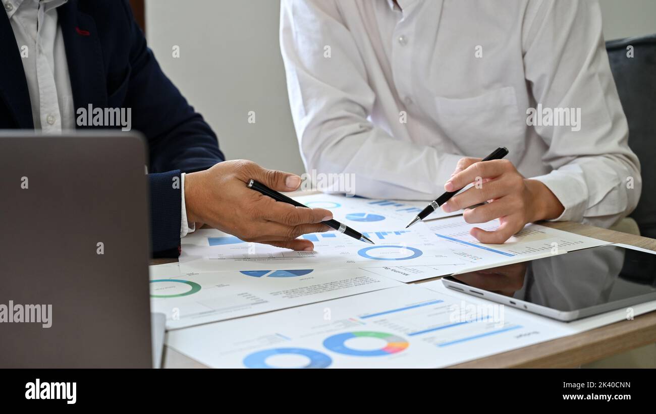 Image rognée, deux hommes d'affaires asiatiques professionnels ou des analystes financiers travaillent, planifient et analysent ensemble les données financières du rapport. Banque D'Images