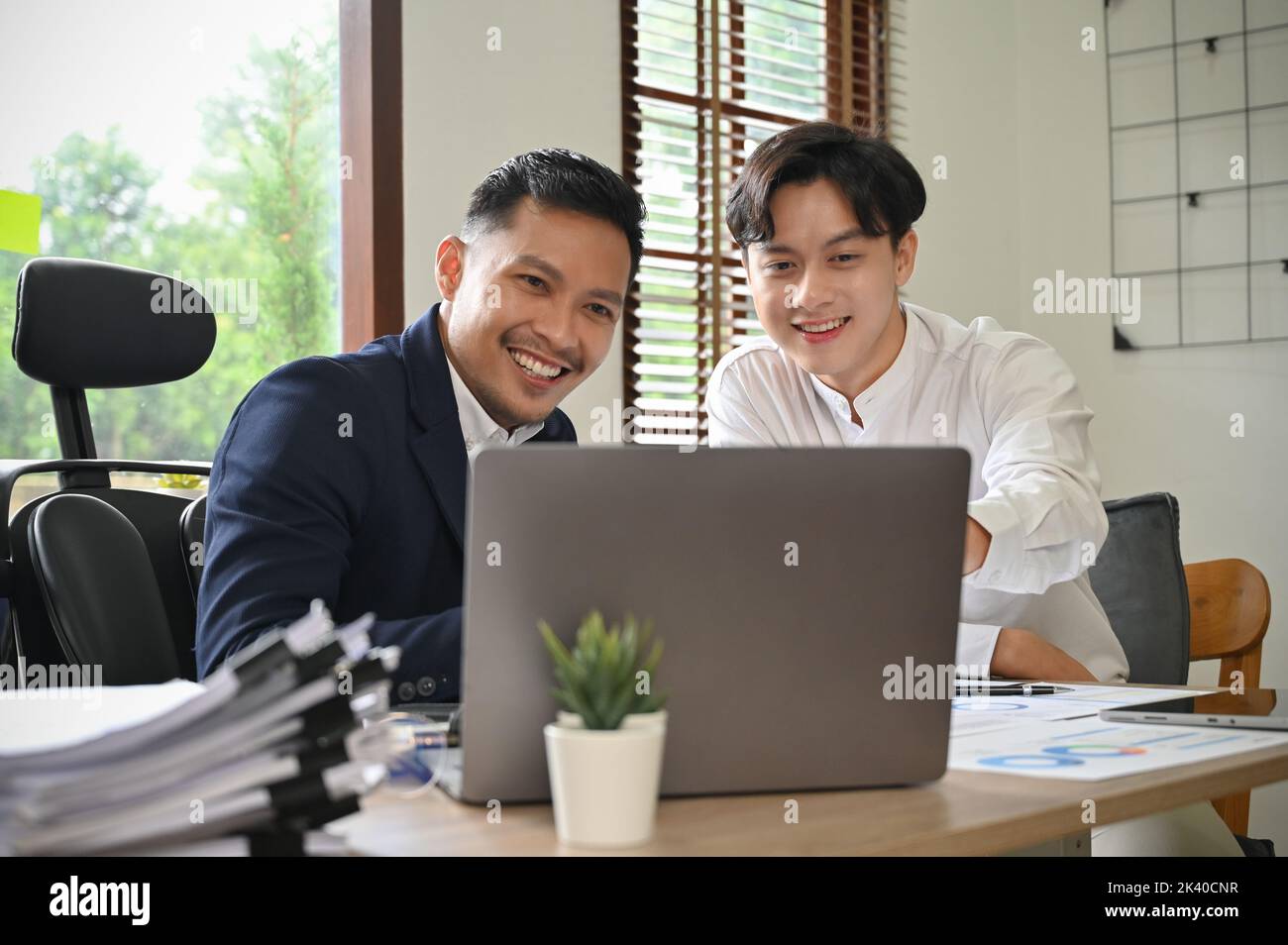 Deux hommes d'affaires asiatiques heureux et professionnels travaillant, partageant des idées entre eux et planifiant leur projet de marketing ensemble. Banque D'Images