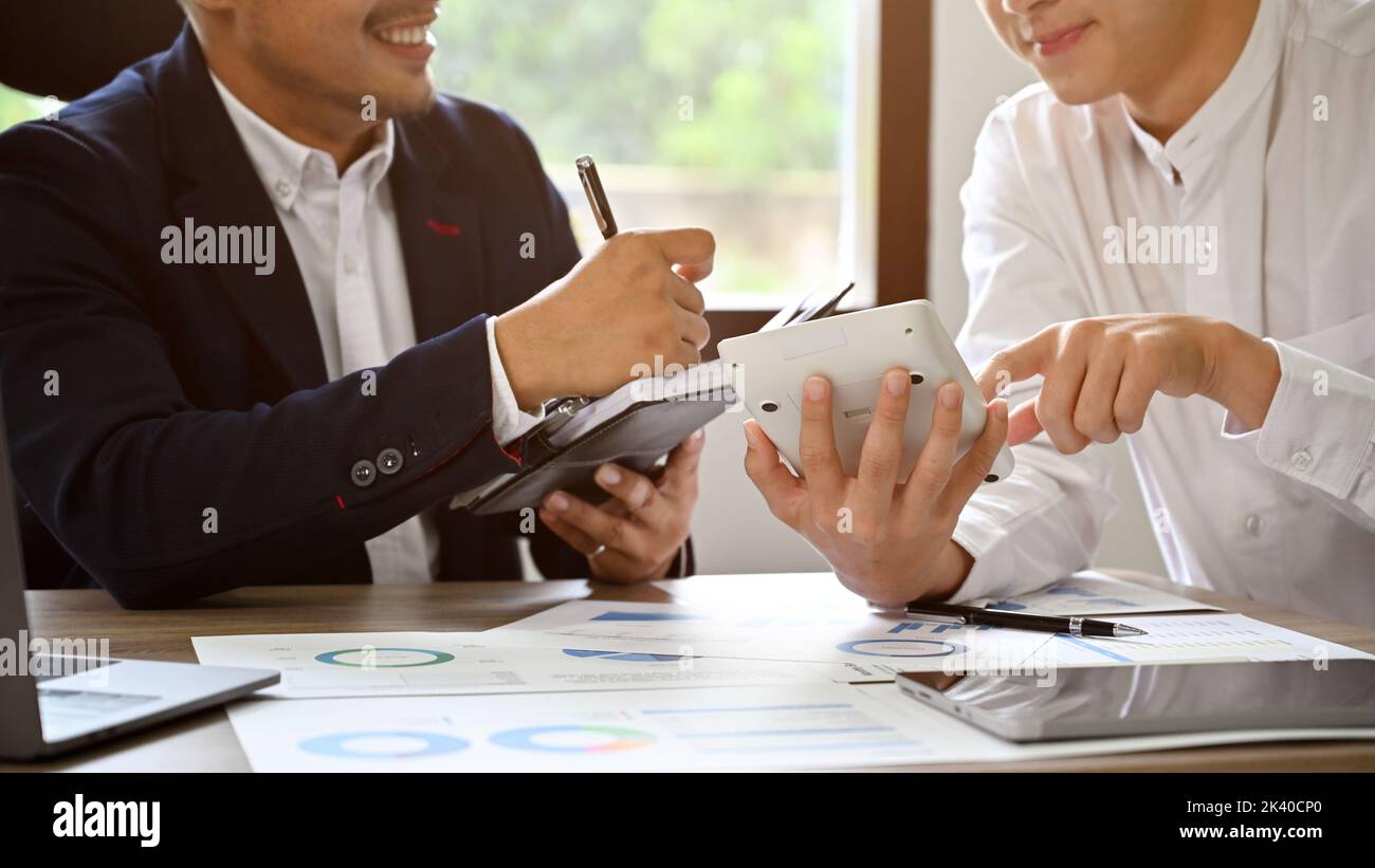 Deux hommes d'affaires asiatiques ou analystes financiers travaillant ensemble, en utilisant la calculatrice, la planification et l'analyse de leur plan d'investissement financier d'affaires togeth Banque D'Images