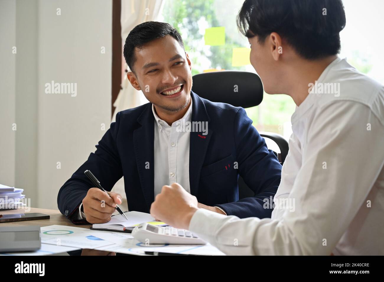 Deux hommes comptables asiatiques ou consultants financiers travaillant ensemble, ayant une belle conversation pendant le travail. Banque D'Images