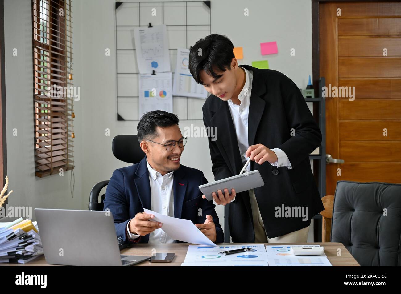 Un patron ou un directeur de direction asiatique pour adultes, intelligent et professionnel, satisfait et satisfait du projet de son employé, travaillant ensemble au bureau. Banque D'Images
