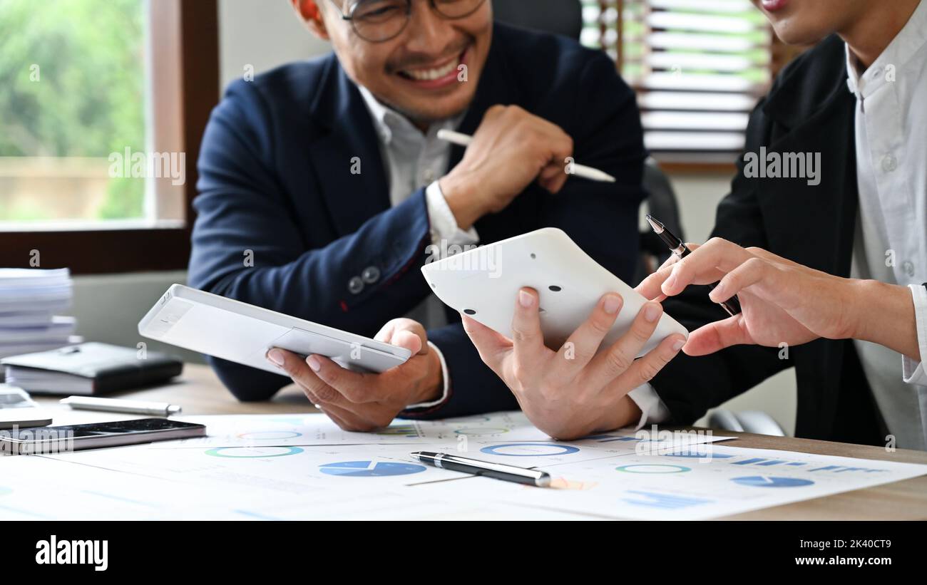 Deux hommes d'affaires asiatiques joyeux et professionnels ou des consultants financiers masculins travaillant ensemble pour calculer et vérifier les données financières. Image rognée Banque D'Images