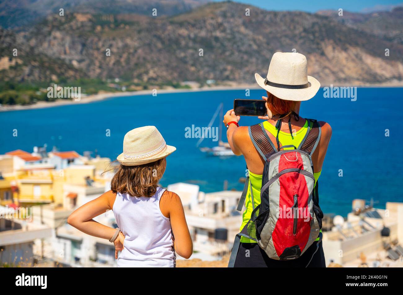 Touristes photographiant un voilier à Paleochora, Crète, Grèce. Mère et fille se tenant au-dessus de la baie de Paléochora, prenant des photos de la baie et Banque D'Images