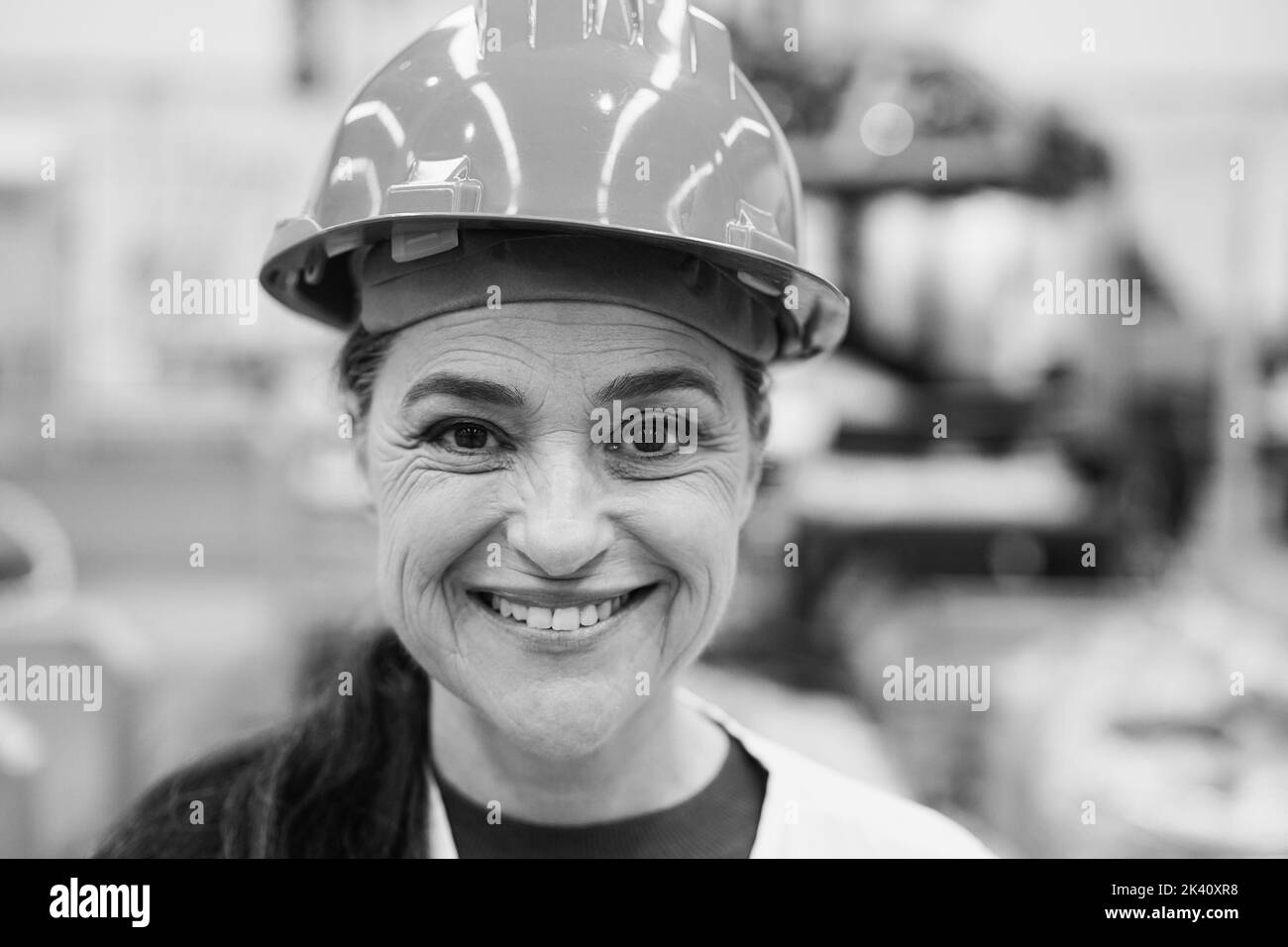 Ingénieur senior femme travaillant dans l'usine robotique - Focus sur hardhat - montage noir et blanc Banque D'Images