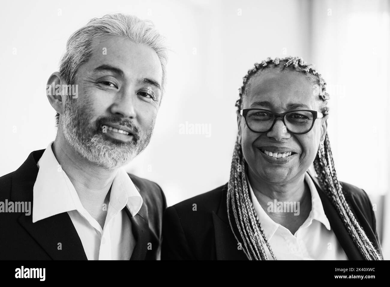 Collègues d'affaires multiraciaux regardant la caméra dans un bureau moderne - Focus sur le visage de femme africaine - montage noir et blanc Banque D'Images