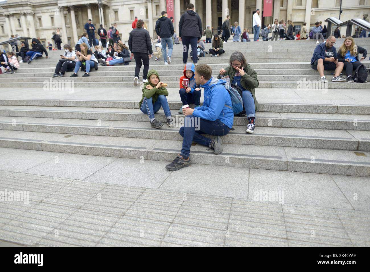 Londres, Angleterre, Royaume-Uni. Jeune famille assis sur les marches de Trafalgar Square menant à la Galerie nationale Banque D'Images