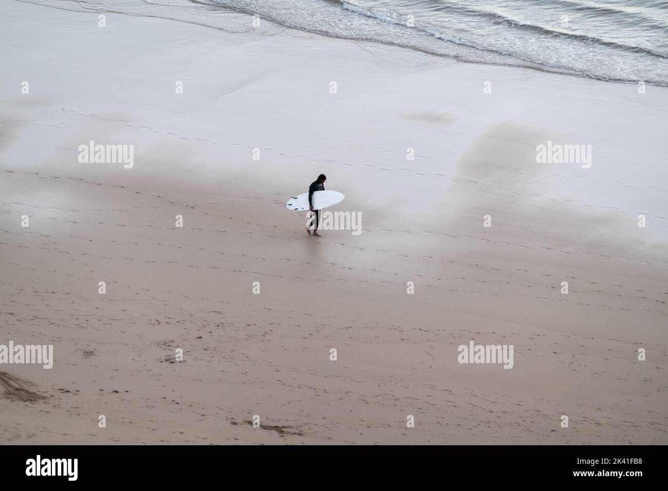 Sagres, Portugal - 30 mai 2022 : image monochrome d'un surfeur à vagues seul mâle à la maison avec surf de la mer le long d'une plage de sable au crépuscule à Sagres Banque D'Images