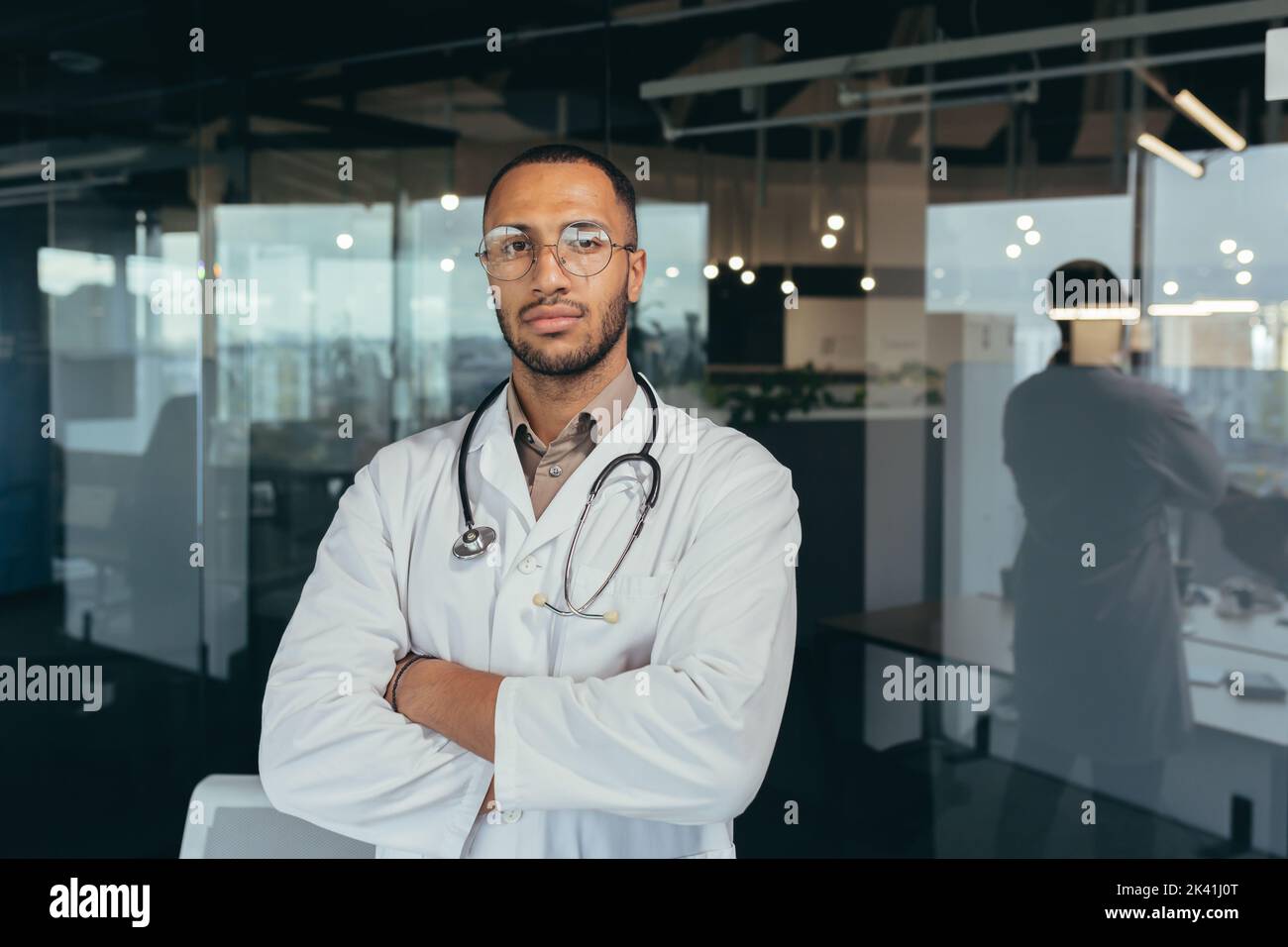 Portrait d'un médecin sérieux et réussi, homme en robe médicale regardant attentivement la caméra, travaillant à l'intérieur d'un immeuble de bureau moderne. Banque D'Images