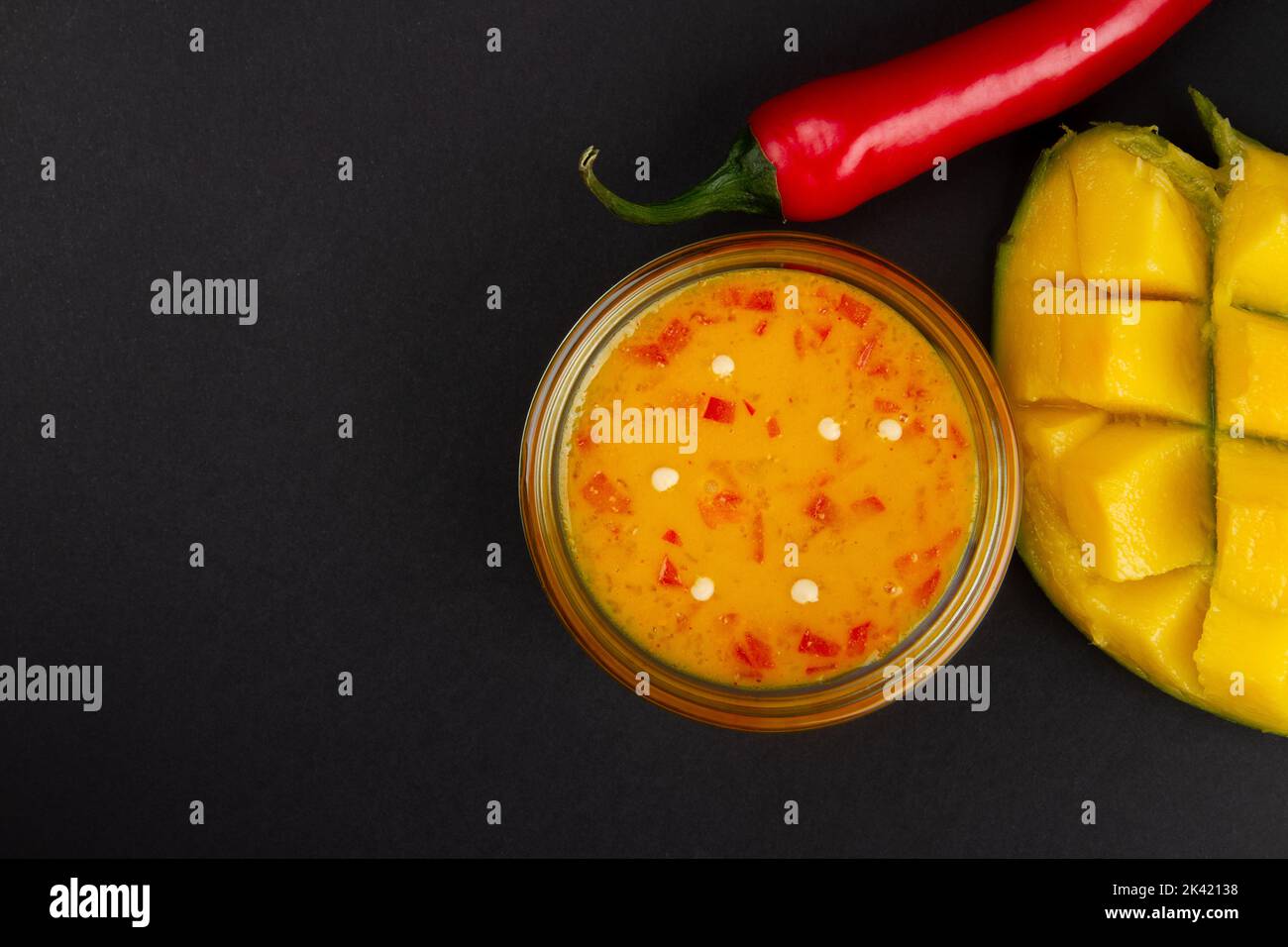 Confiture de mangue au piment, mangue coupée et piment rouge sur fond gris foncé avec espace libre pour le texte Banque D'Images