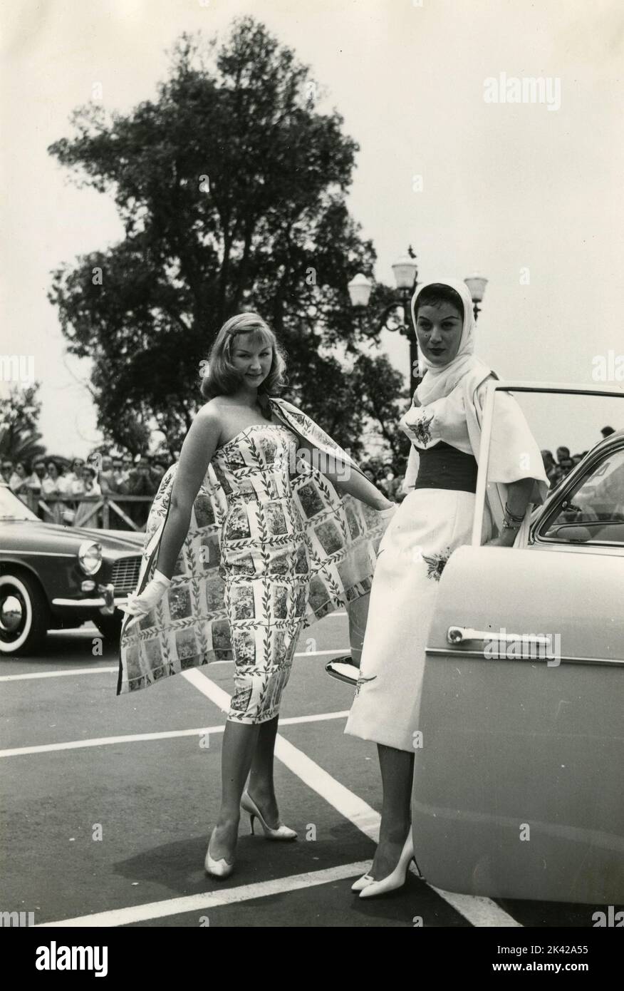 Deux modèles montrant leurs robes à côté d'une voiture, Rome, Italie 1950s Banque D'Images