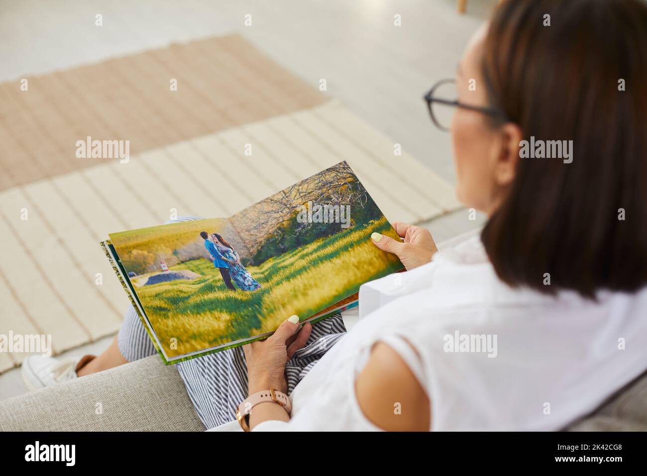 Femme âgée regardant à travers des photos dans son album photo de famille ou livre de mémoire Banque D'Images