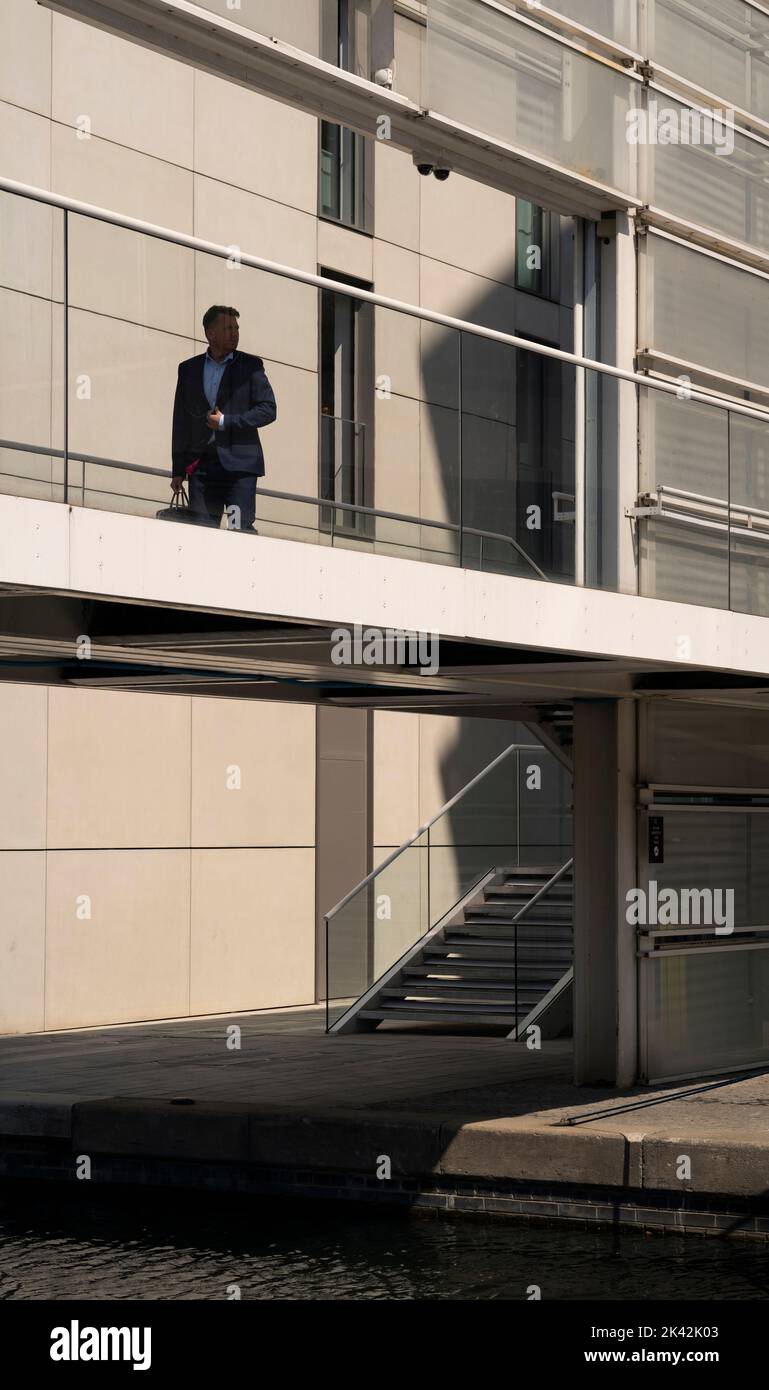 Homme d'affaires en silhouette traversant un pont depuis un immeuble de bureaux au-dessus du canal Grand Union au nord-ouest de Londres Banque D'Images