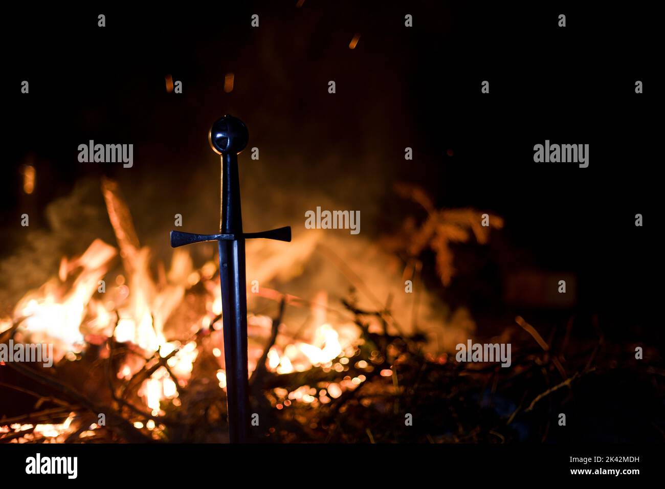 Gros plan de l'épée des Templiers dans le sol par le feu Banque D'Images