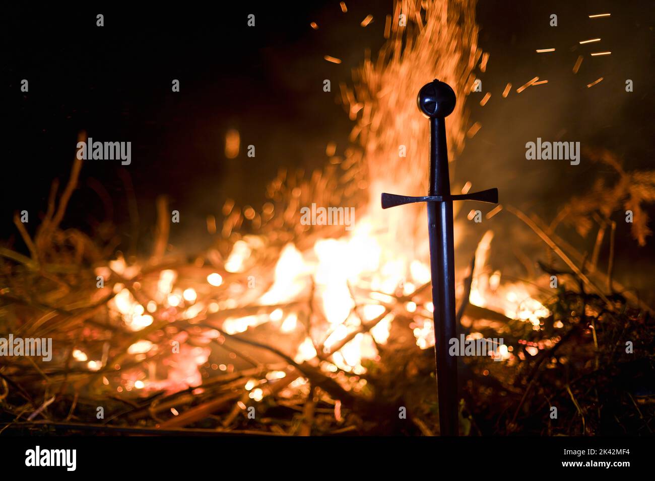 Gros plan de l'épée des Templiers dans le sol par le feu Banque D'Images