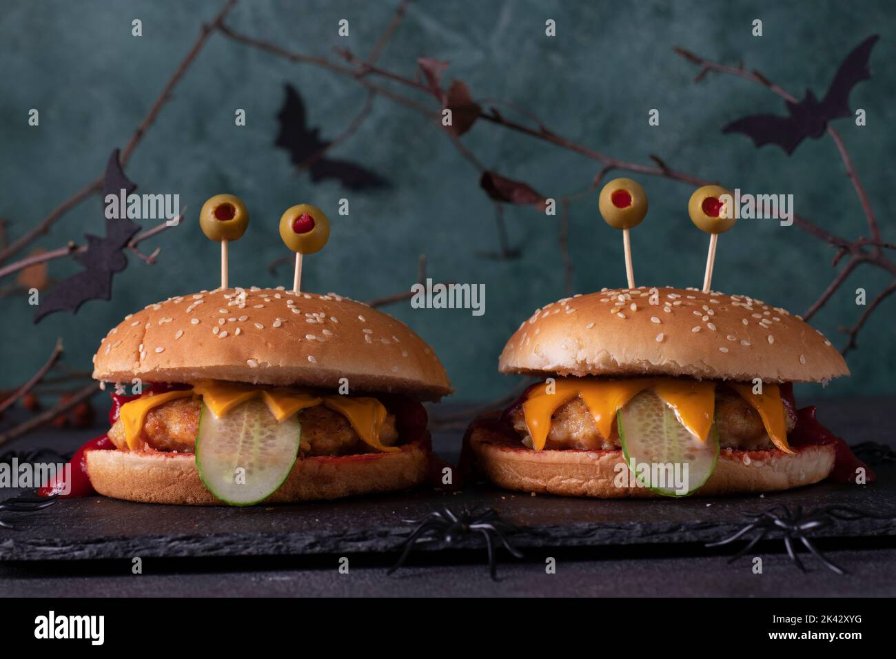 Deux burgers de poulet monstre drôle avec toasts au fromage, ketchup, concombre et yeux d'olive. Cuisine créative d'Halloween Banque D'Images