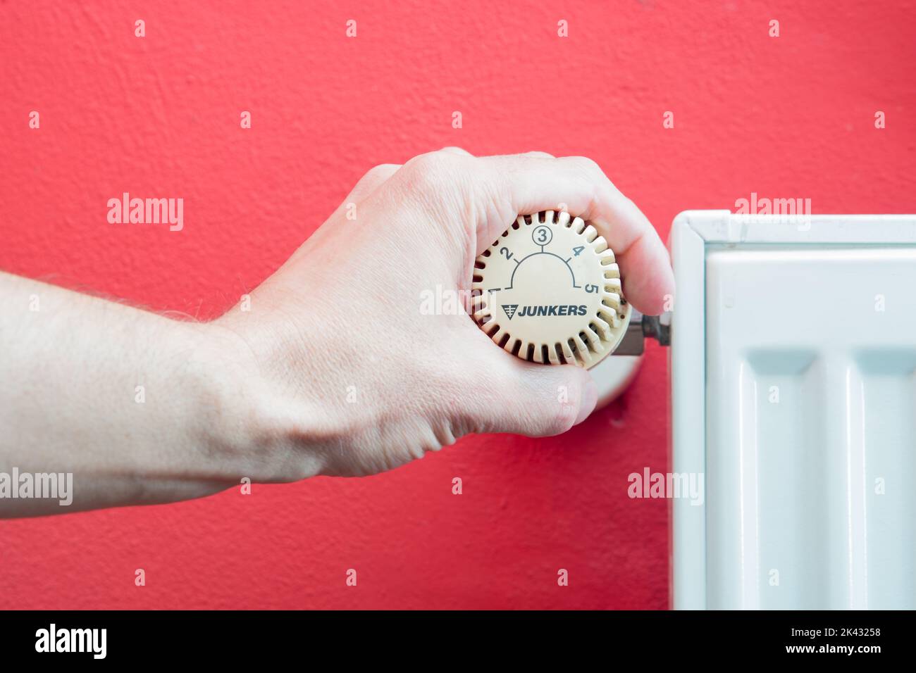 Maintenir le thermostat sur le radiateur à la main pour régler la température. Crise énergétique en Europe. Électricité coûteuse et manque de gaz. Les prix augmentent. Banque D'Images