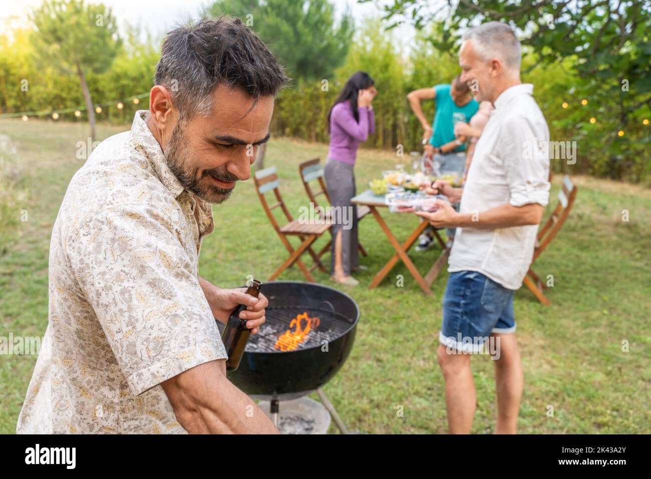 Les gens autour du barbecue sourient heureux et rient ensemble. Concept de joie. Banque D'Images