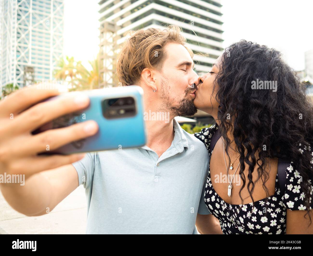 Divers couple hétérosexuel dans l'amour embrassant tout en prenant un selfie. Amoureux, lune de miel Banque D'Images