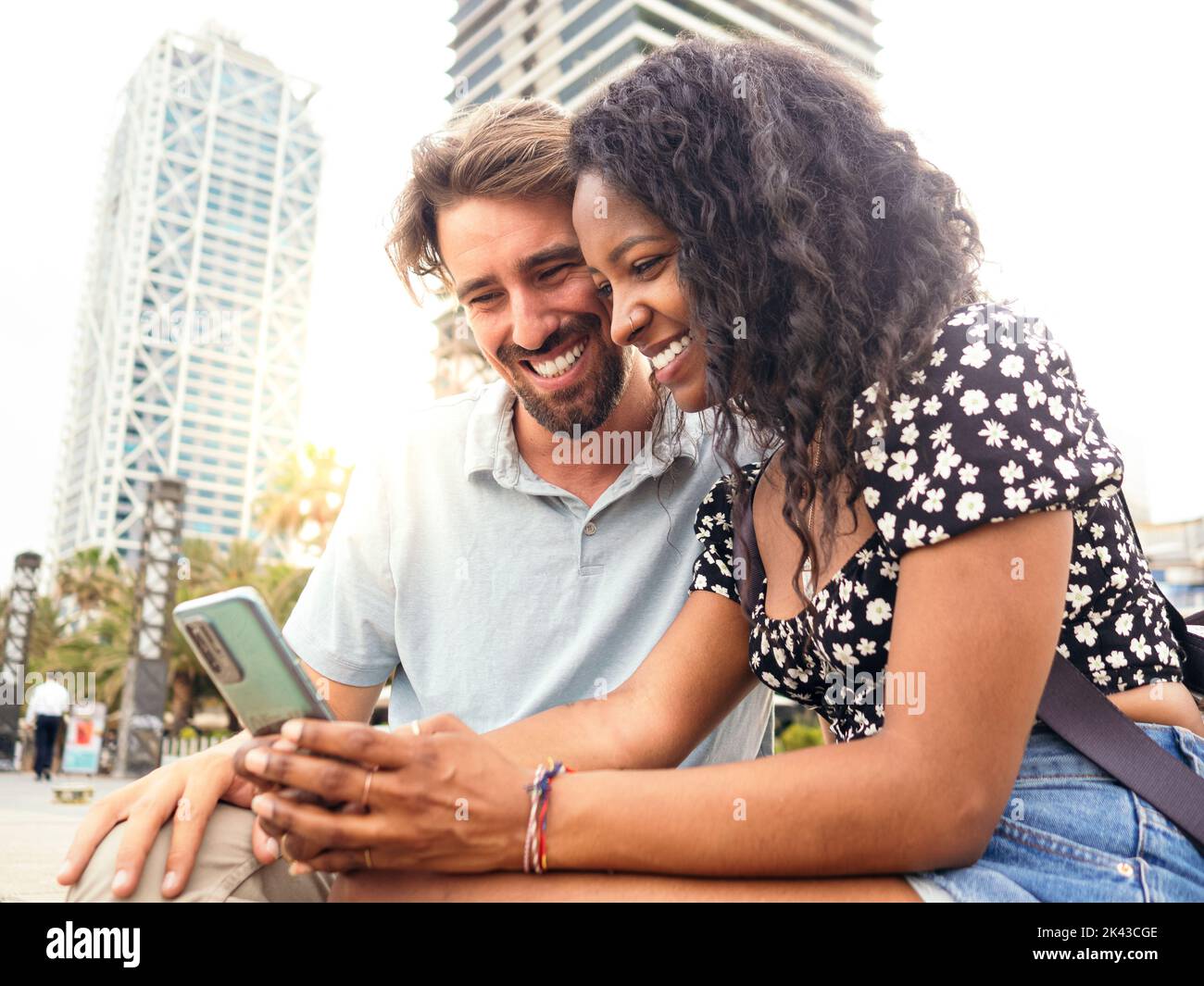 Jeune couple hétérosexuel multiethnique regardant un téléphone mobile dans la ville Banque D'Images