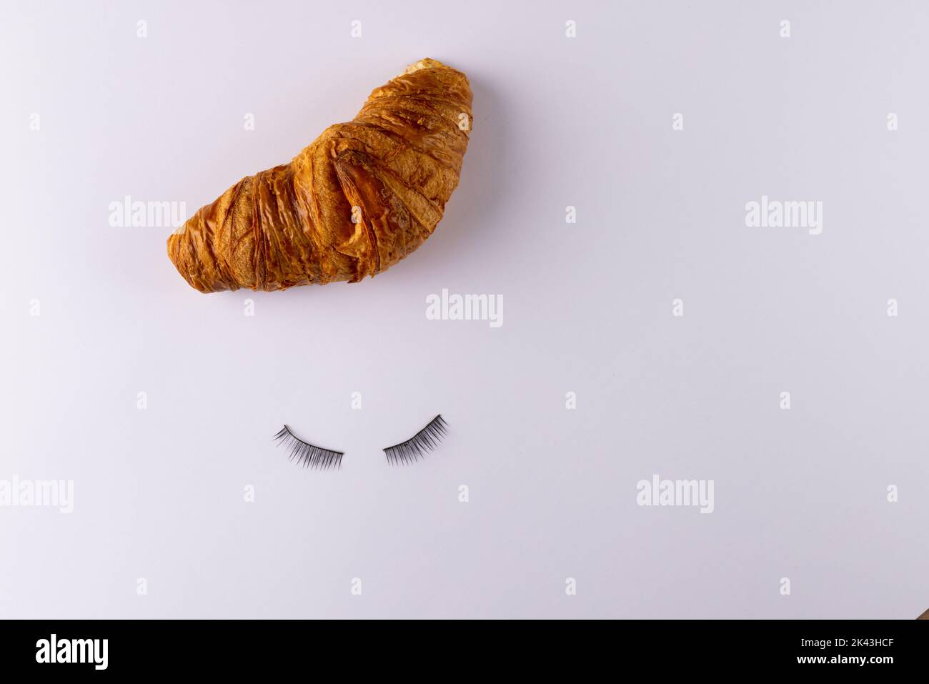 Image de croissant et faux cils couchés sur fond blanc Banque D'Images