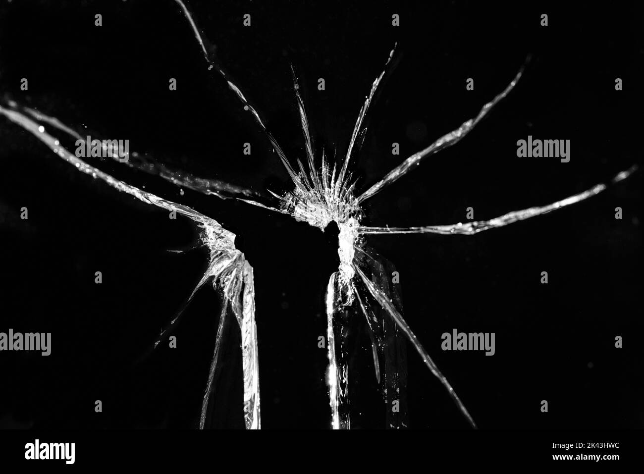 Gros plan d'un panneau de verre cassé et fissuré avec trou, sur fond noir Banque D'Images