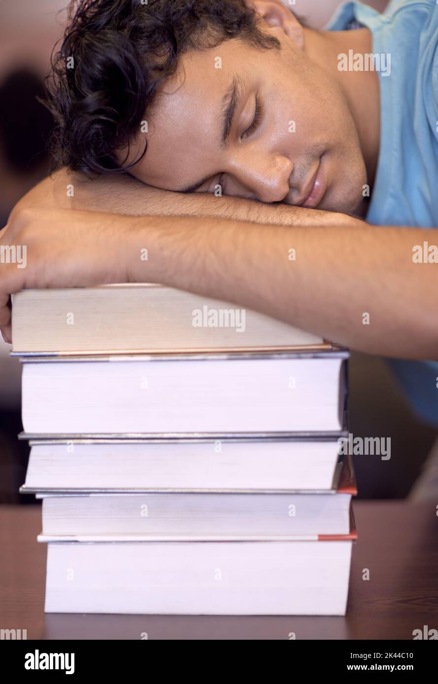 L'heure de l'examen lui a été donnée. Un jeune étudiant dormant sur son bureau après une session d'étude fatigante. Banque D'Images