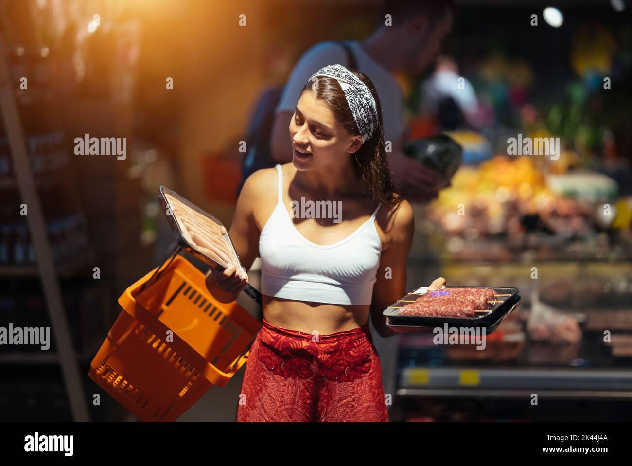 Une jeune femme choisit de la viande dans une épicerie Banque D'Images
