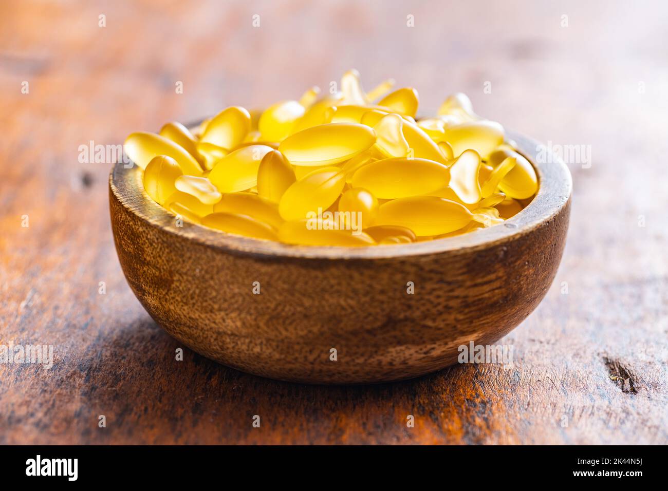 Capsules d'huile de poisson dans un bol. Pilules jaunes omega 3 sur la table en bois. Banque D'Images