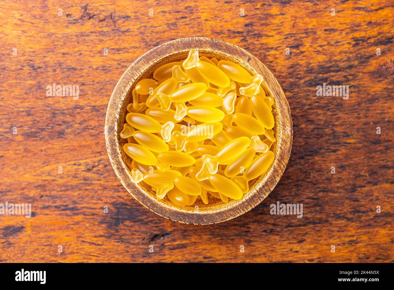 Capsules d'huile de poisson dans un bol. Pilules jaunes omega 3 sur la table en bois. Vue de dessus. Banque D'Images