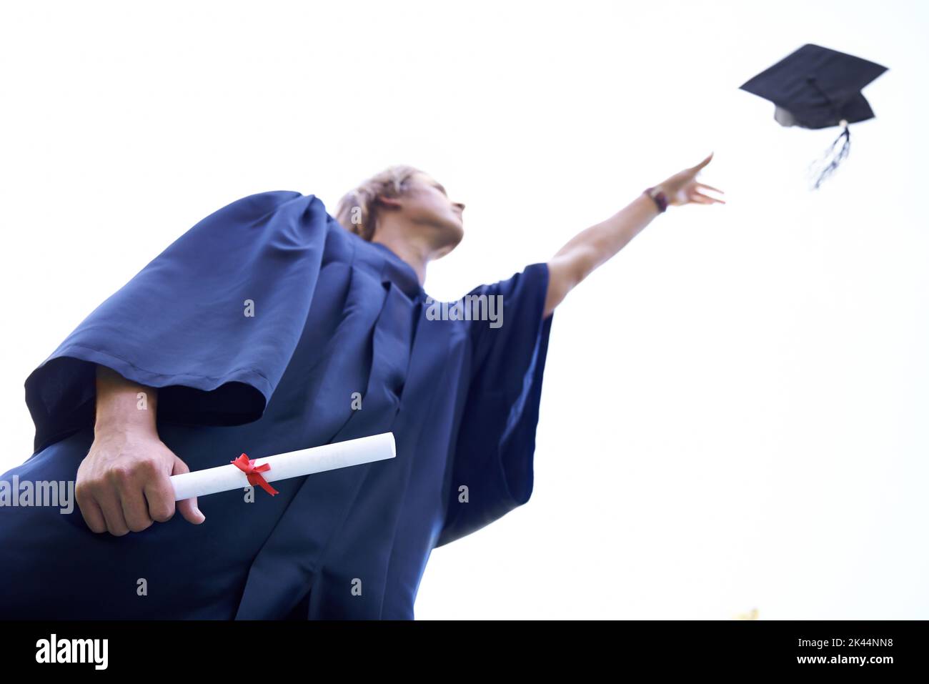 Je l’ai fait. Un diplômé qui jette son chapeau de diplômé dans les airs tout en tenant son diplôme. Banque D'Images