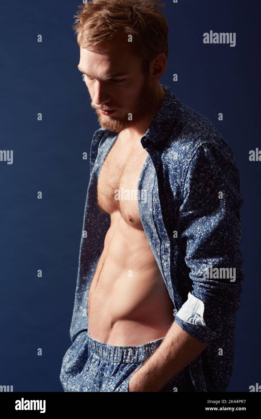 Un moment de mélancolie. Un jeune homme musclé portant une chemise ouverte et regardant loin. Banque D'Images