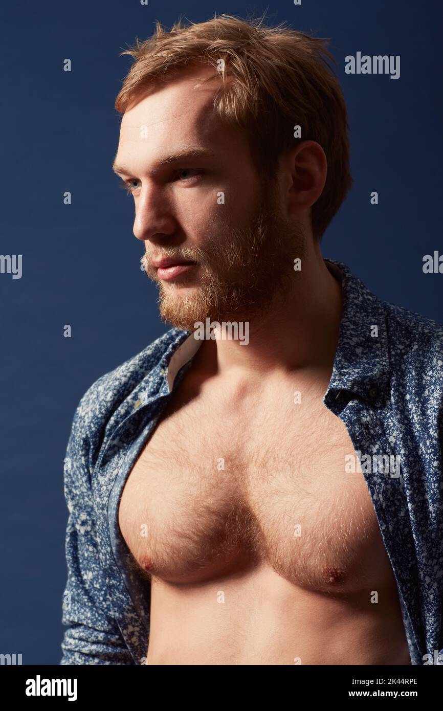 Style unique. Un jeune homme musclé portant une chemise ouverte et regardant loin. Banque D'Images