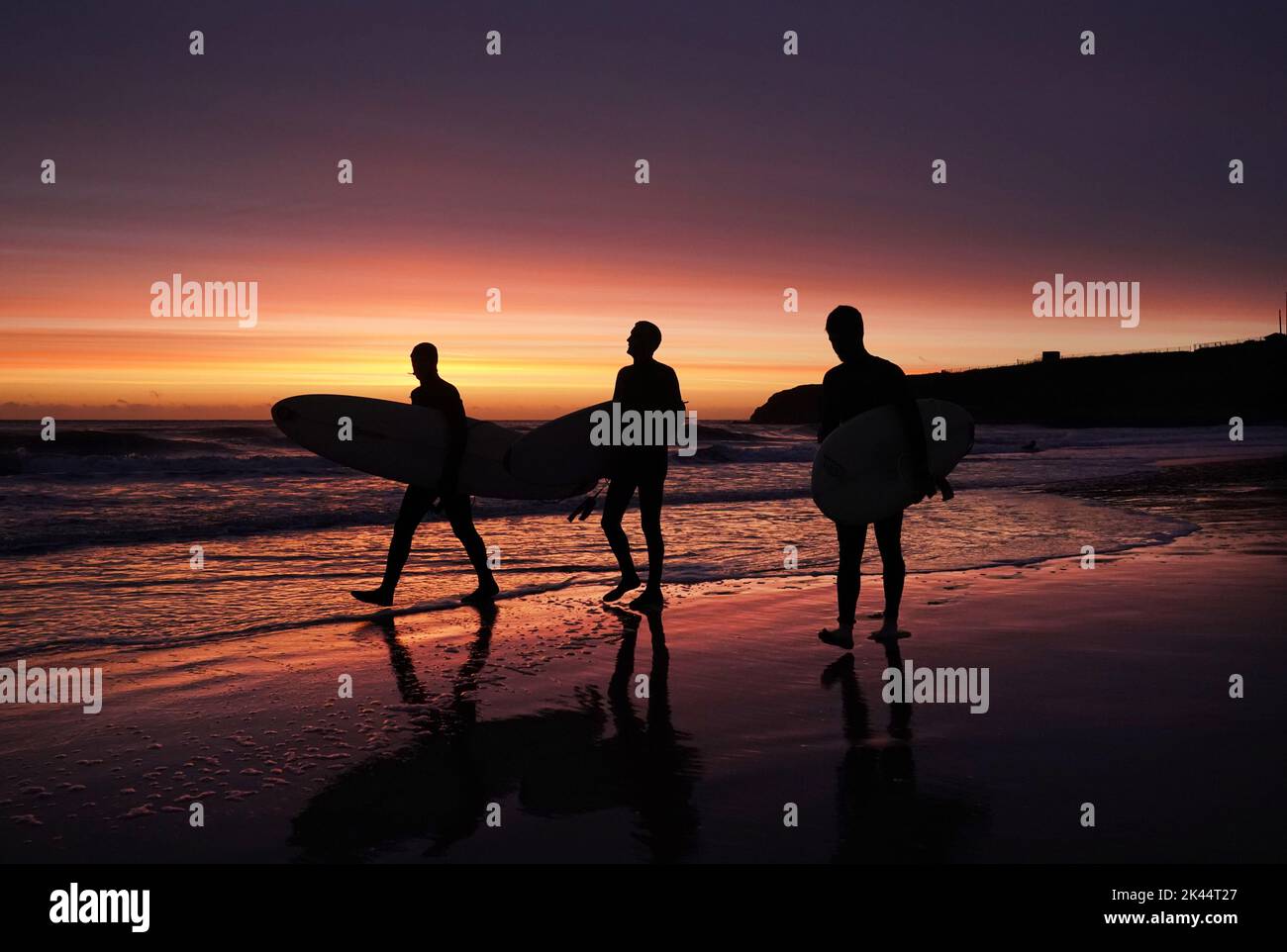Les surfeurs pénètrent dans l'eau à la plage de Tynemouth Longsands avant le lever du soleil. Date de la photo: Vendredi 30 septembre 2022. Banque D'Images