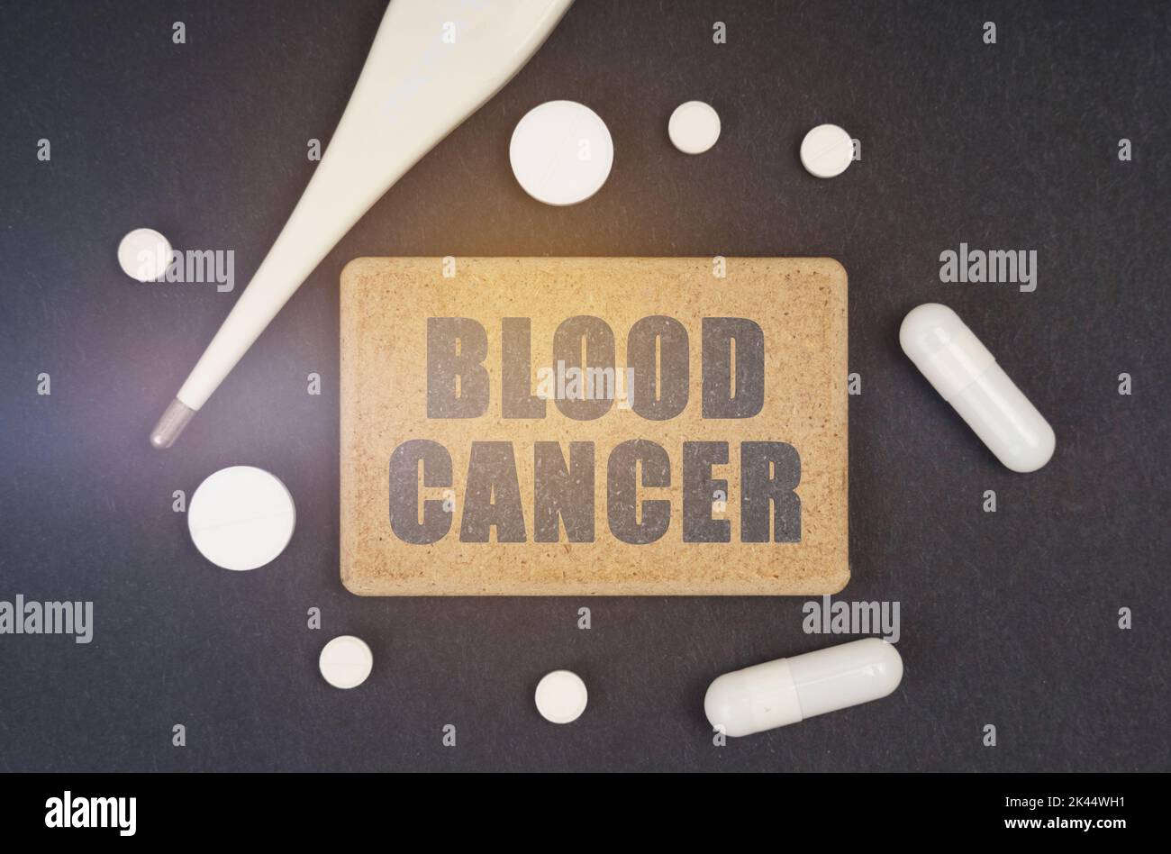 Concept de médecine. Sur fond noir, un thermomètre, des pilules et une plaque avec l'inscription - CANCER DU SANG Banque D'Images