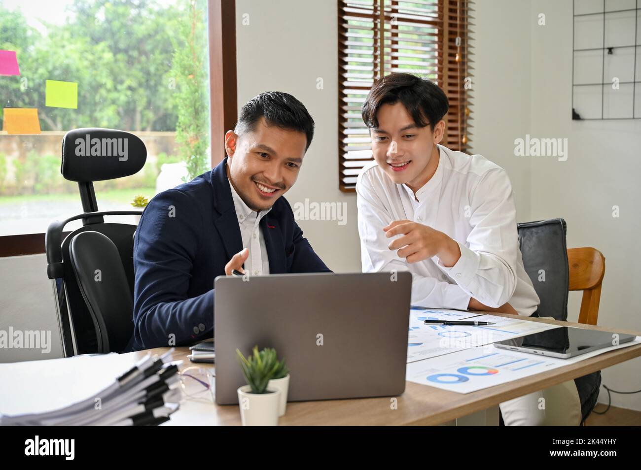 Concept de travail d'équipe, deux collègues d'affaires asiatiques travaillant au bureau, vérifiant leur projet sur un ordinateur portable ensemble. Banque D'Images