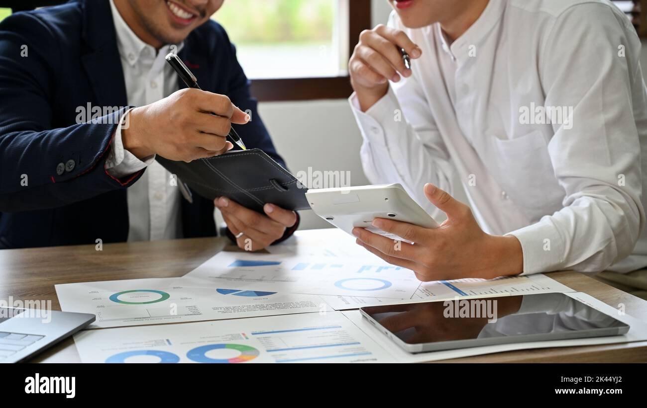 Des conseillers financiers masculins asiatiques intelligents utilisant la calculatrice, analysant les données financières sur le rapport, la réunion et de travailler ensemble. Image rognée Banque D'Images