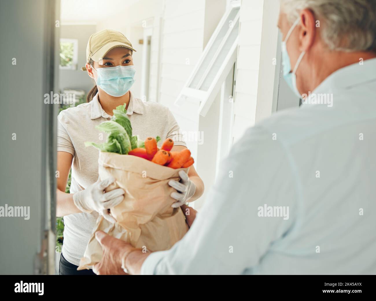 Livraison de nourriture, virus et vieil homme dans le masque de visage pendant la collecte de covid épicerie et des légumes sains à la maison. Volontaire pandémique donnant des personnes âgées Banque D'Images