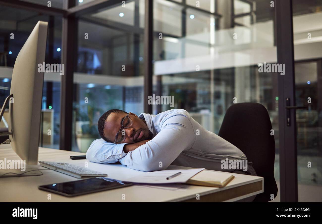 Affaires de nuit, sommeil de travail et homme d'affaires dormant au bureau avec ordinateur dans bureau sombre dans une entreprise. Manager ou employé africain fatigué Banque D'Images