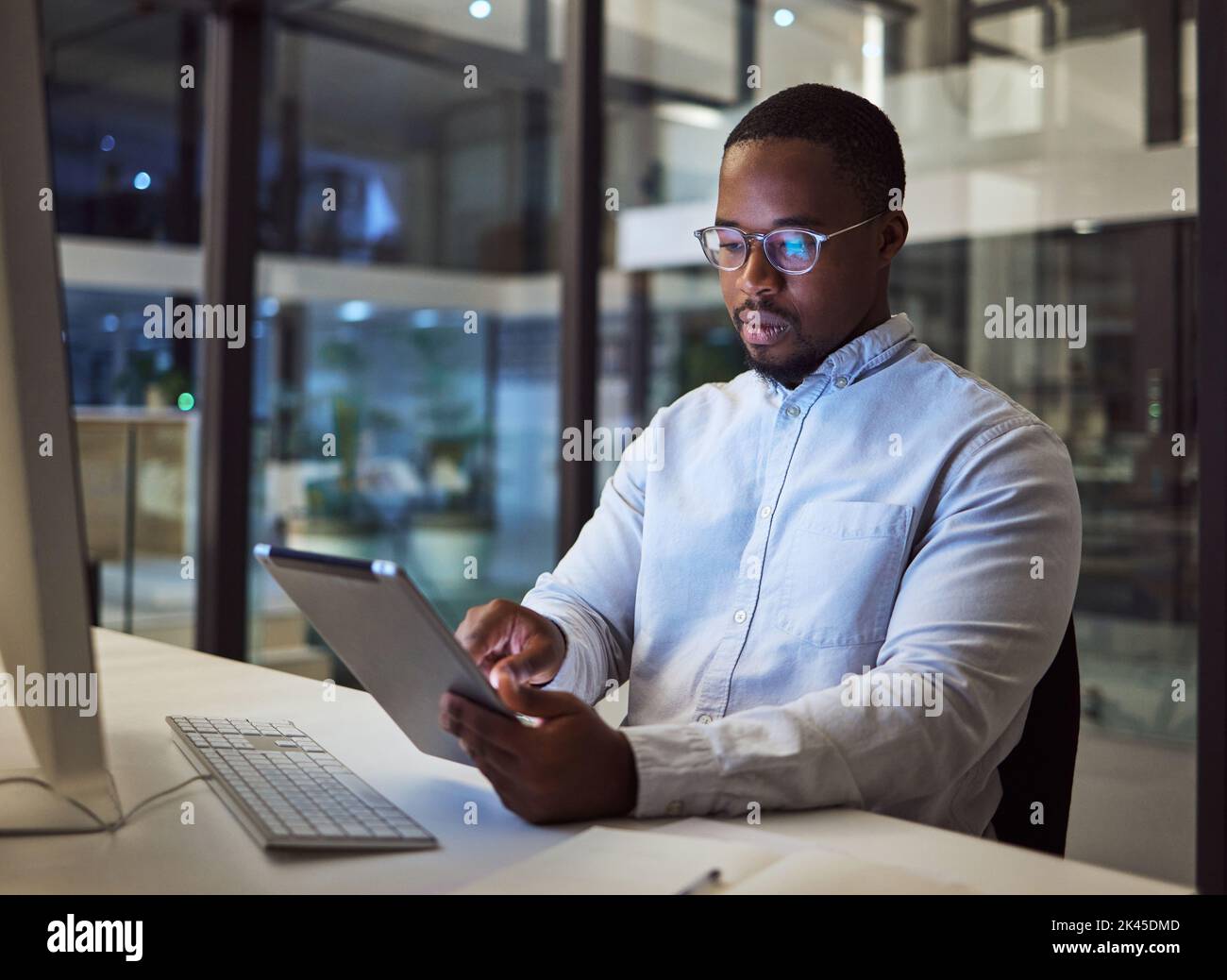 Homme d'affaires noir, tablette et analyse de données avec ordinateur dans le bureau de nuit pour les logiciels de marketing numérique, le code de cybersécurité ou kpi. Penser Banque D'Images
