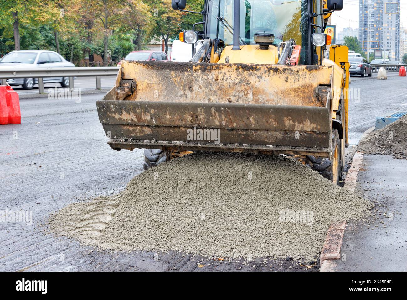 Chargeur sur roues à mini-chargeuse jaune chargement et déchargement du mélange de gravier de sable sur route. Le concept de construction et de réparation. Banque D'Images
