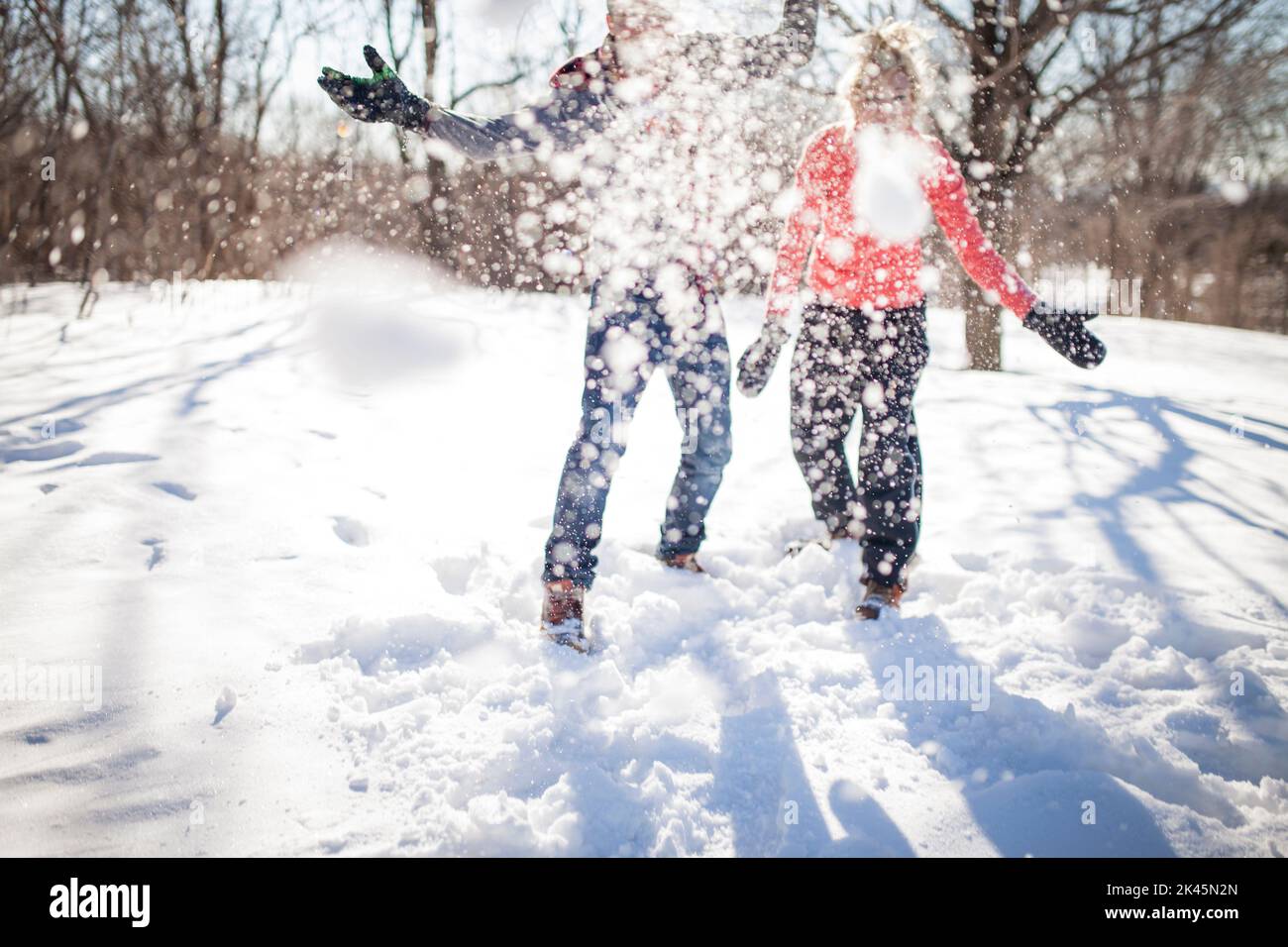 Couple qui jette un ballon de neige à la caméra dans le parc. Banque D'Images