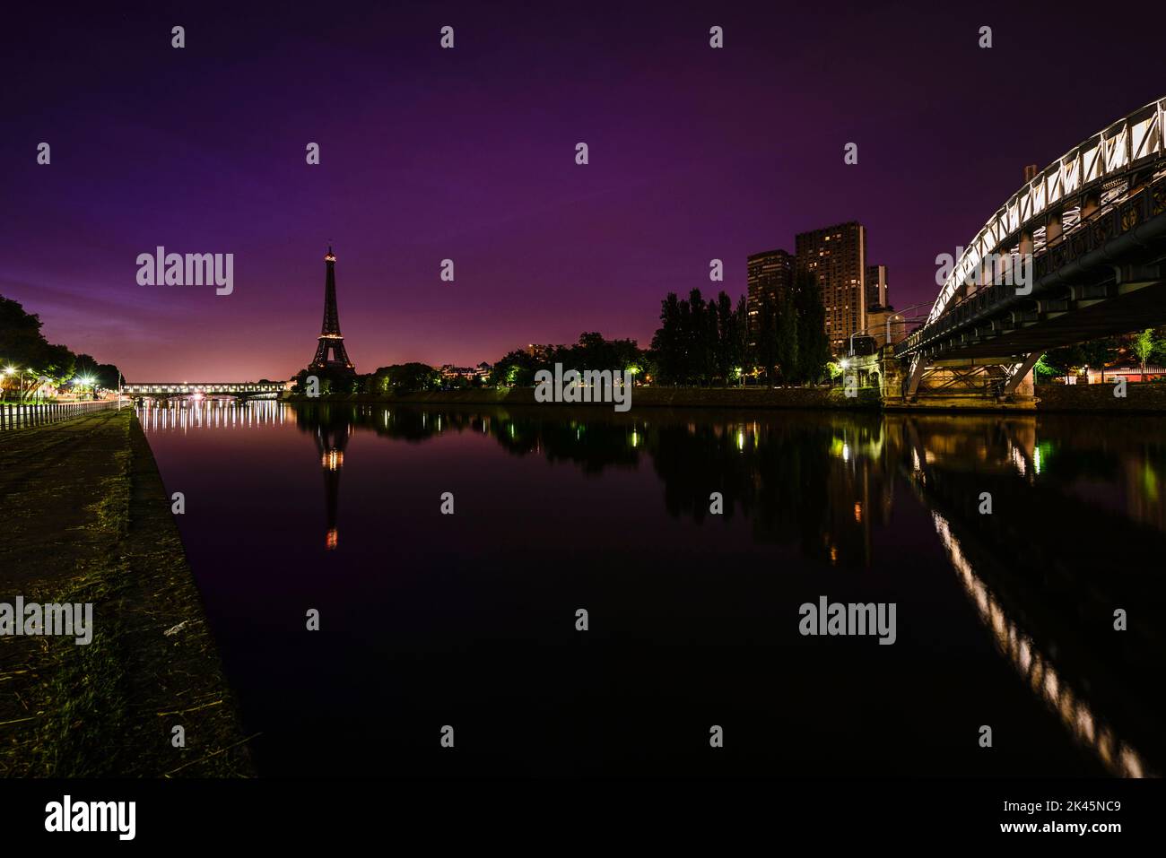 La ville la nuit, vue sur la Seine jusqu'à la Tour Eiffel, bâtiments et routes éclairés. Banque D'Images