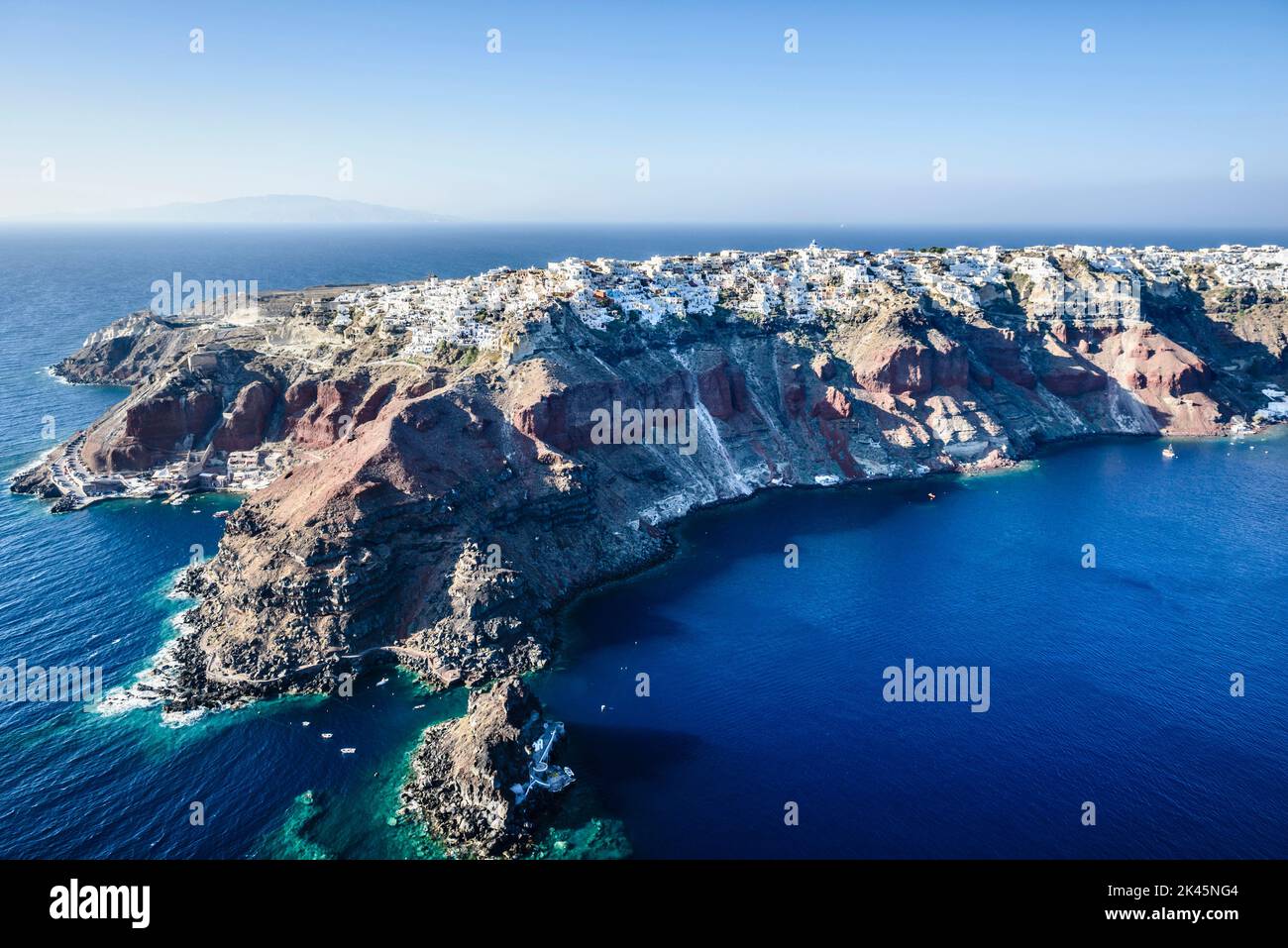 Vue aérienne d'une île dans les mers bleu profond de la mer Égée, formations rocheuses, maisons blanchies à la chaux perchées sur les falaises. Banque D'Images