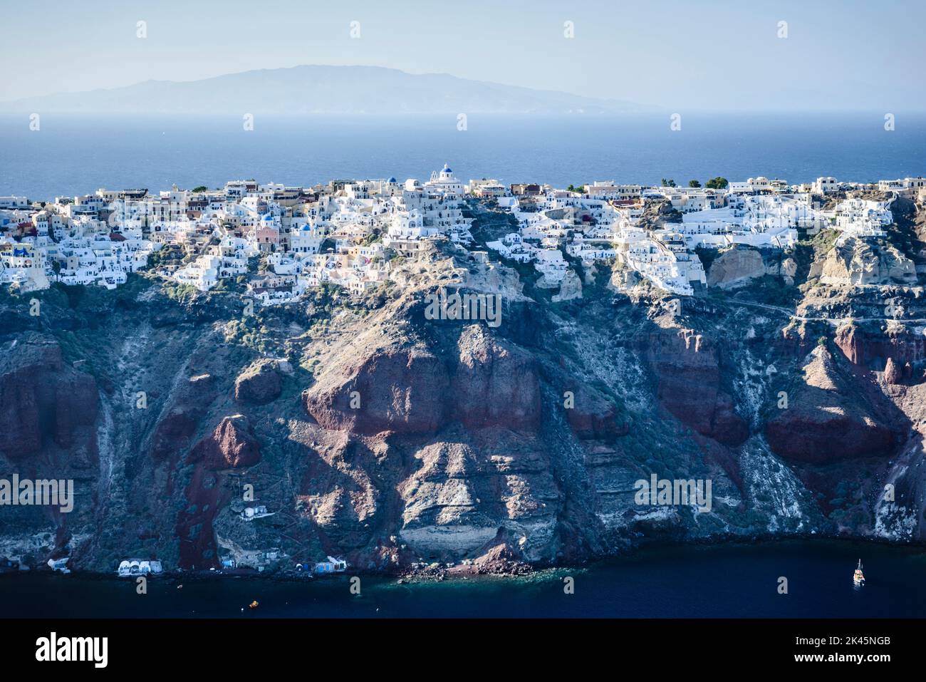 Vue aérienne d'une île dans les mers bleu profond de la mer Égée, formations rocheuses, maisons blanchies à la chaux perchées sur les falaises. Banque D'Images