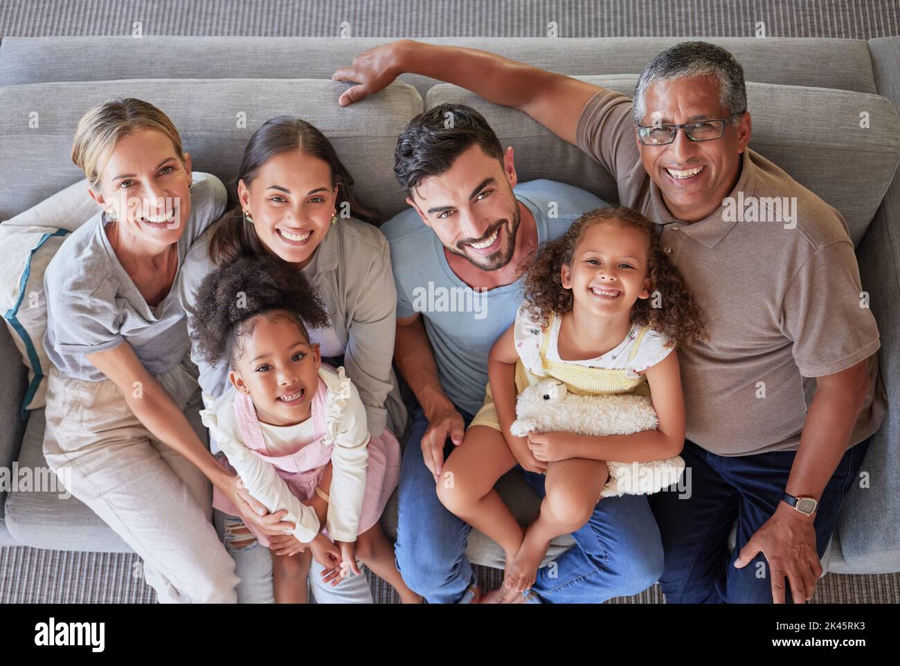 Souriez, bonne famille sur le canapé et vue sur les générations, grands-parents et parents ensemble dans le salon. Portrait de diversité, amour et couple Banque D'Images