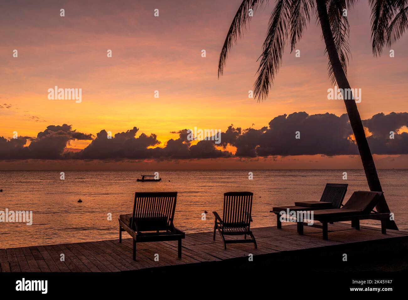 Un magnifique lever de soleil avec un cadre tropical paisible depuis une terrasse sur le rivage met en évidence la belle matinée pour commencer une nouvelle journée. Banque D'Images