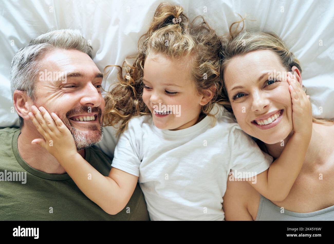 Famille, heureux et sourire des personnes d'en haut dans le lit à la maison se détendre dans une chambre. Mère, fille et homme avec bonheur dans une maison avec amour Banque D'Images