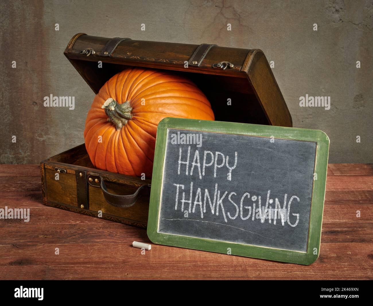 Carte de vœux Happy Thanksgiving - panneau de tableau blanc à la craie avec une grande citrouille dans une petite valise rétro Banque D'Images