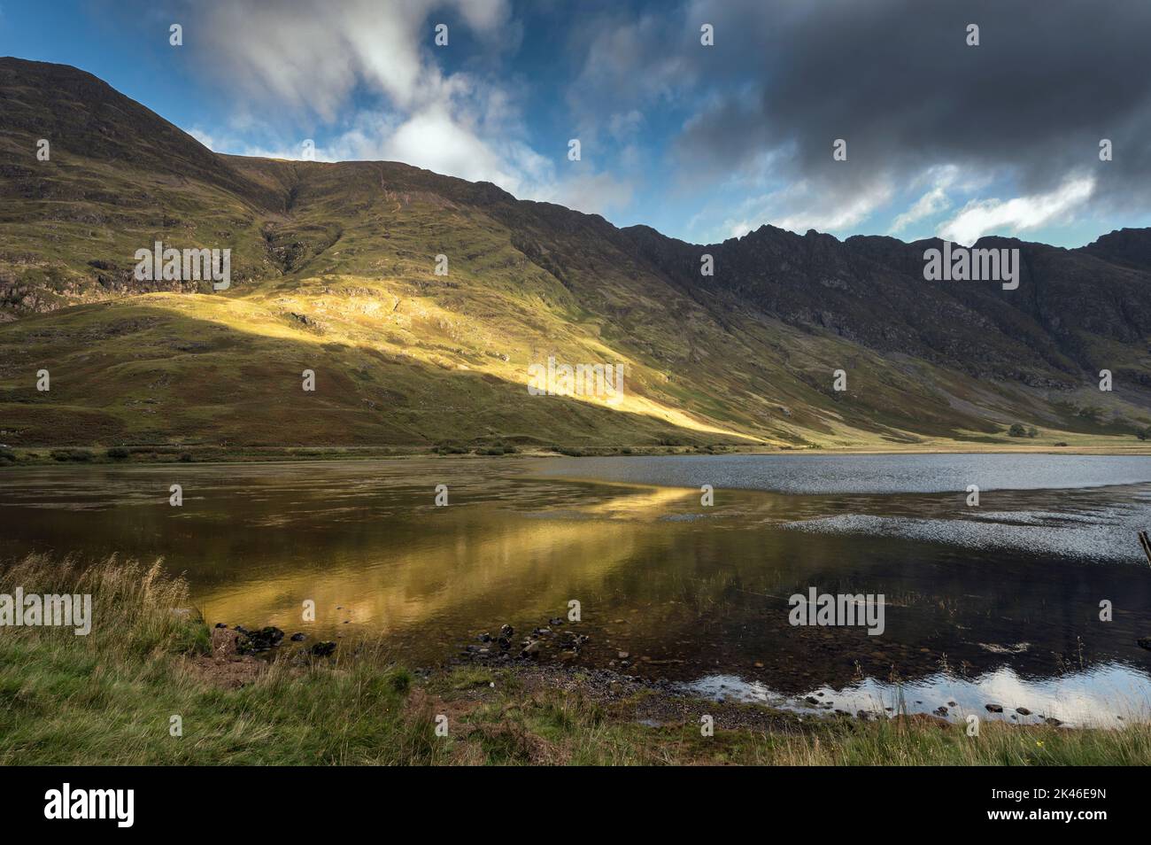 Le soleil se brisant à travers les nuages peint les pentes de montagne de Glencoe en Écosse Banque D'Images